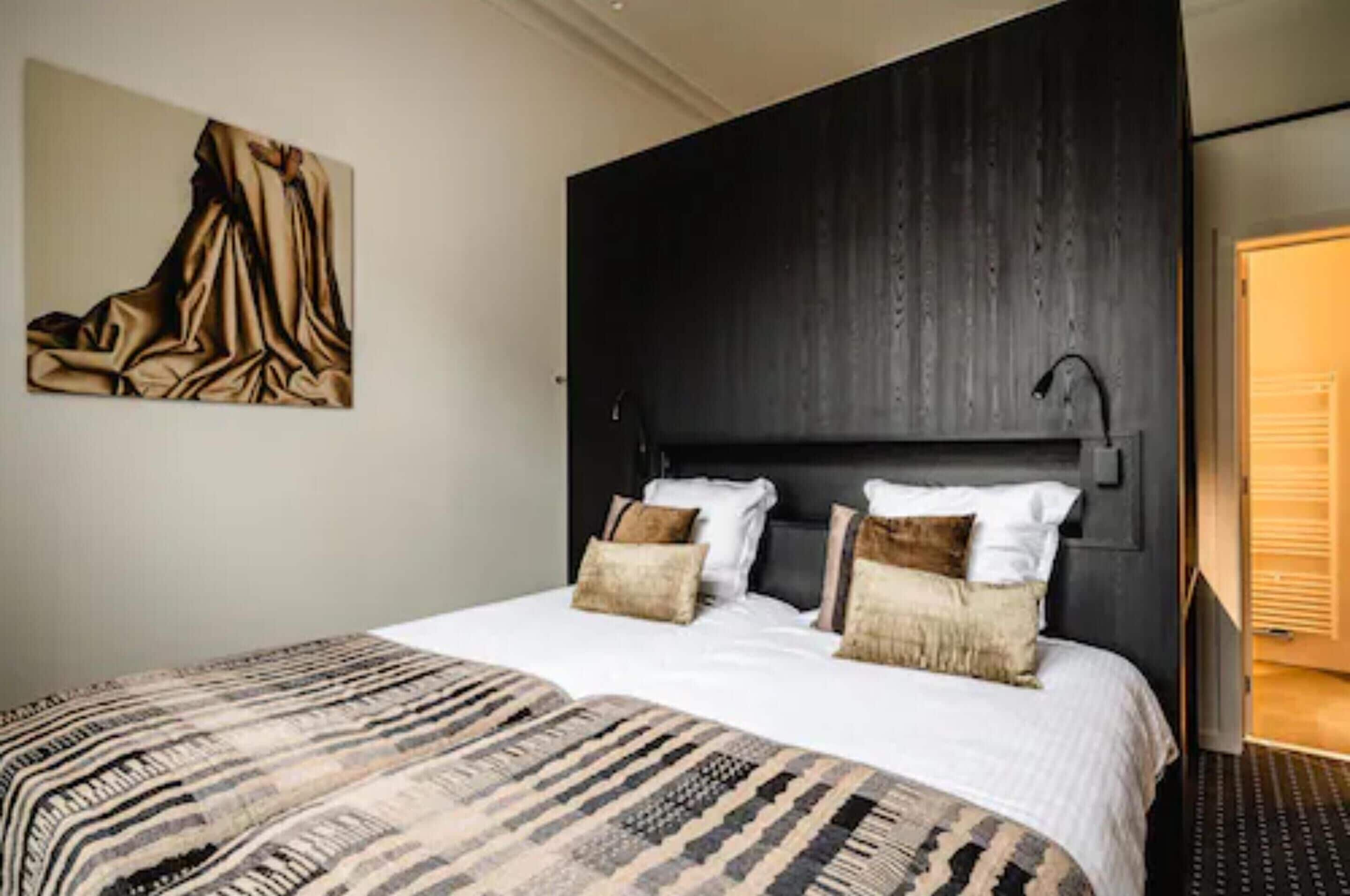 Un dormitorio moderno con una cama grande, cabecera de madera oscura y un cuadro en la pared.