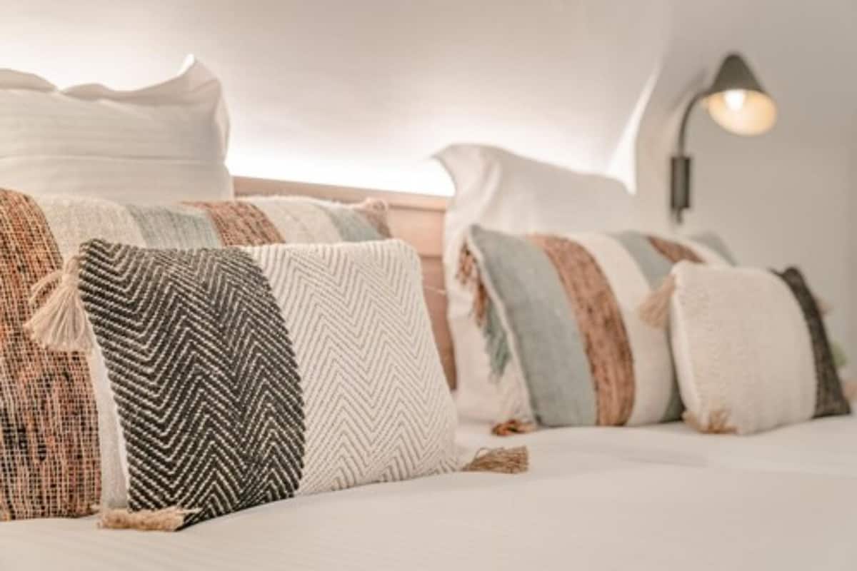 A neatly made bed with striped and textured pillows.