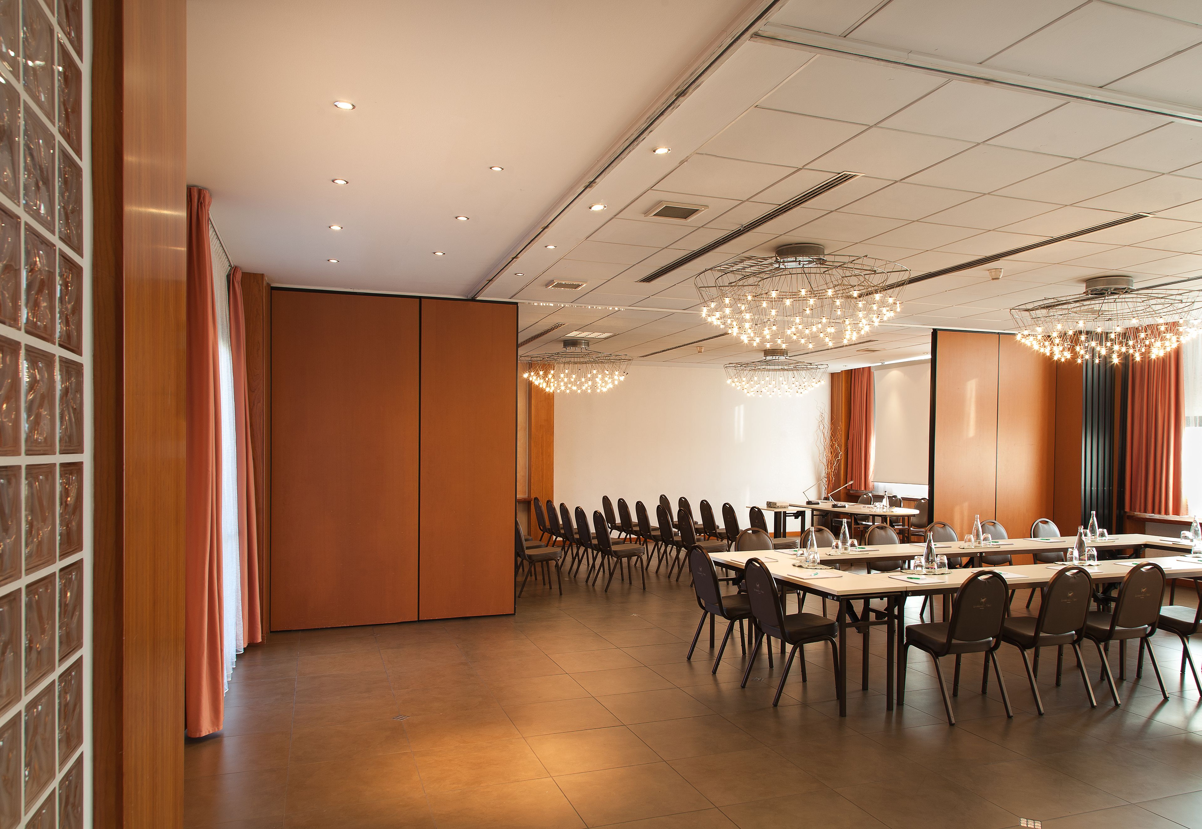 A conference room with a long table, chairs, and a large screen.