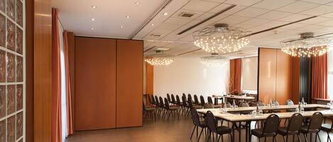 A conference room with a long table, chairs, and a large screen.