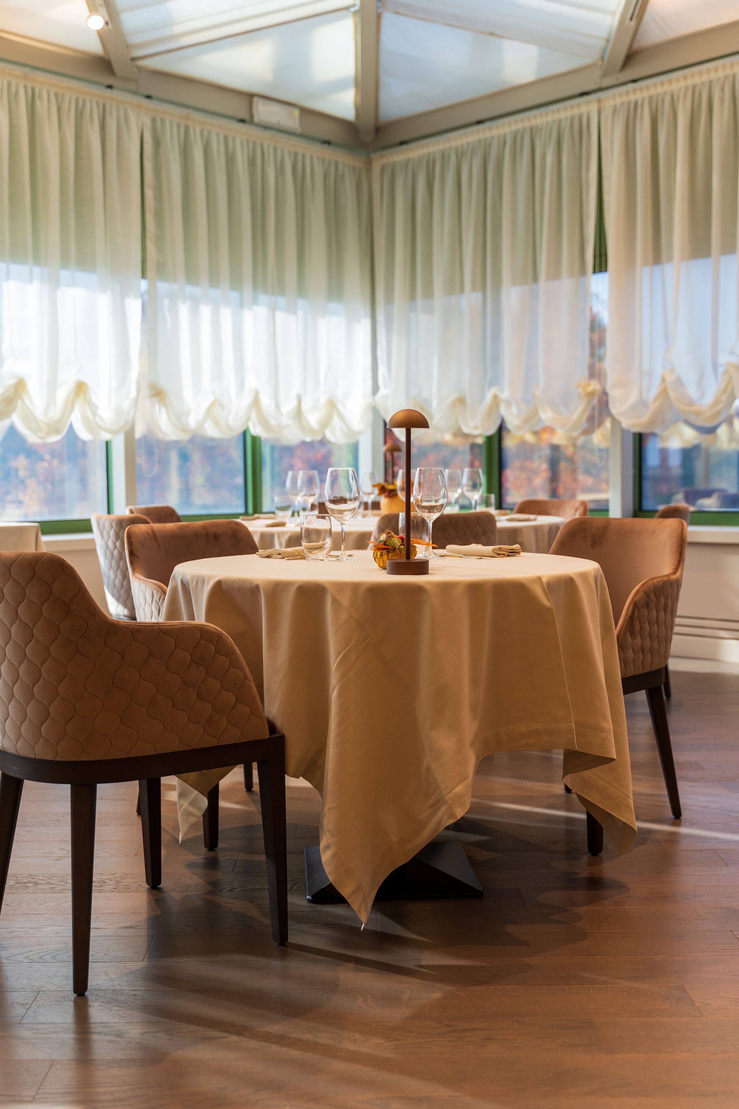 A dining area with round tables, chairs, and a view through large windows.