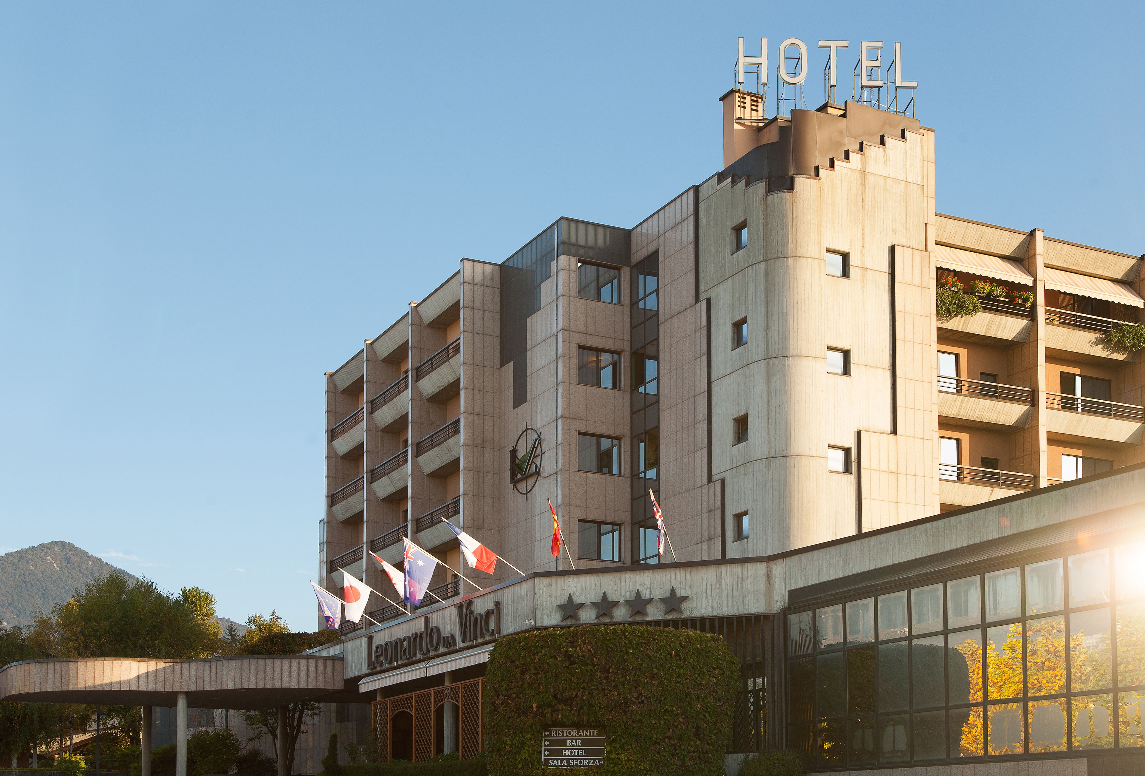 A hotel with a modern design, featuring a prominent 'HOTEL' sign, multiple balconies, and flags.