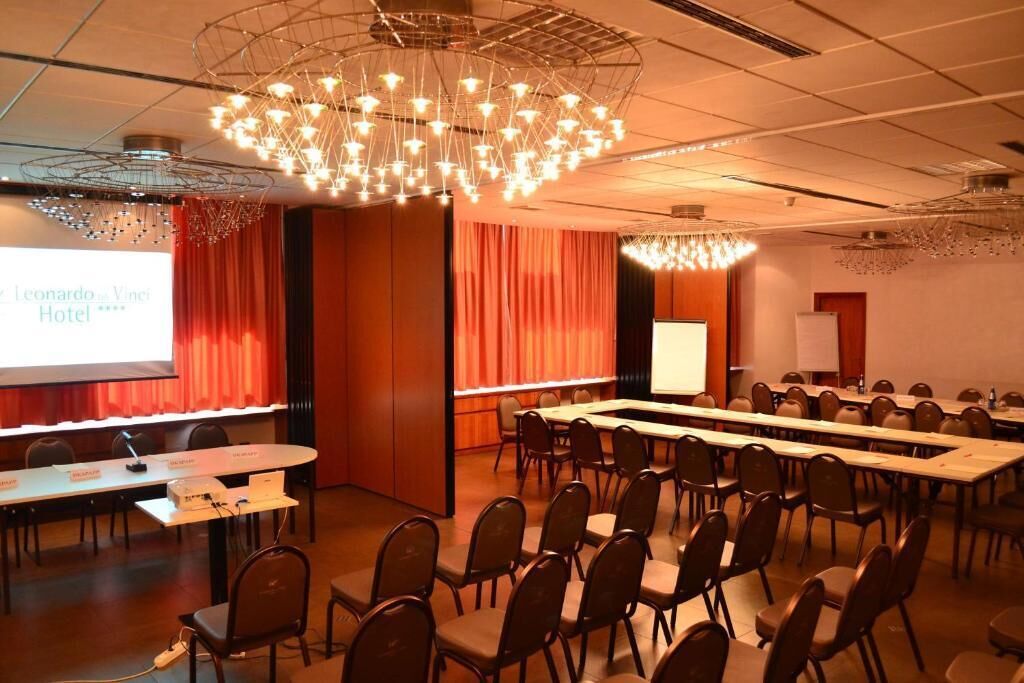 Een vergaderzaal met een lange tafel, stoelen, een projectiescherm en een kroonluchter.