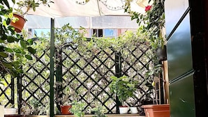 A small outdoor patio with a table and two chairs, surrounded by potted plants and a lattice fence. - Ca' Riza (Venice)
