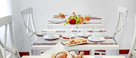 Une table de petit-déjeuner dressée avec des croissants, des fruits, des œufs et du jus.