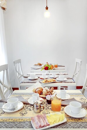 A breakfast table set with croissants, fruit, eggs, and juice. - Ca' Riza (Venice)