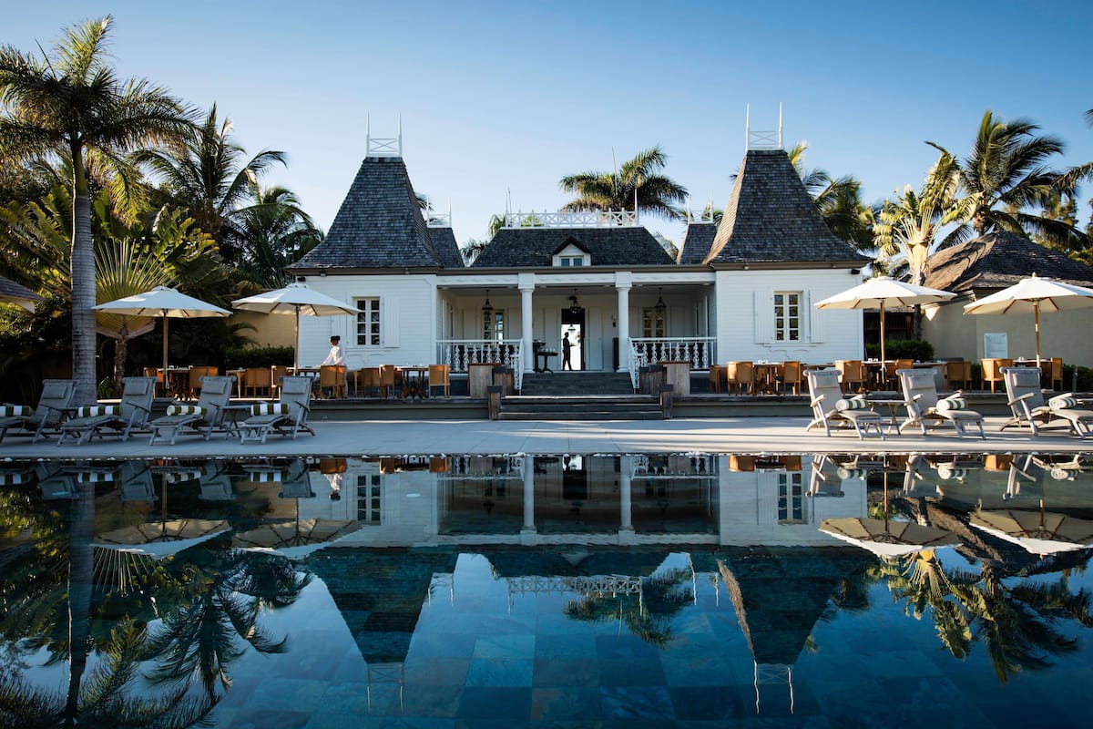 A resort with a pool, lounge chairs, and palm trees.