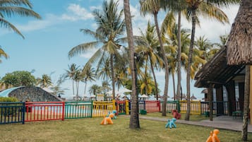 Un resort tropical con palmeras, un área de piscina y estructuras de juego coloridas.