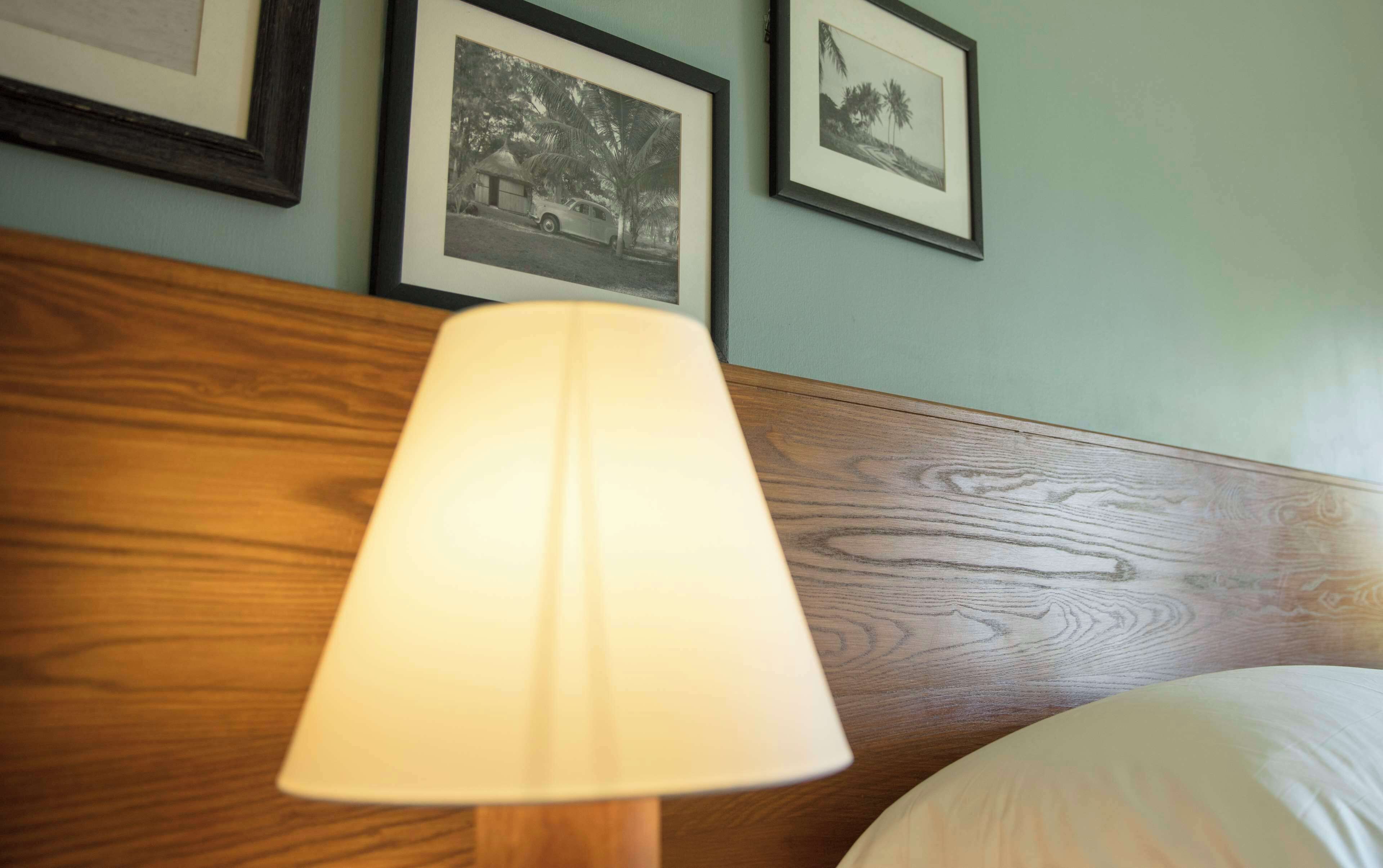 Ein Bett mit Holz-Kopfteil, einer Nachttischlampe und gerahmten Bildern an der Wand.