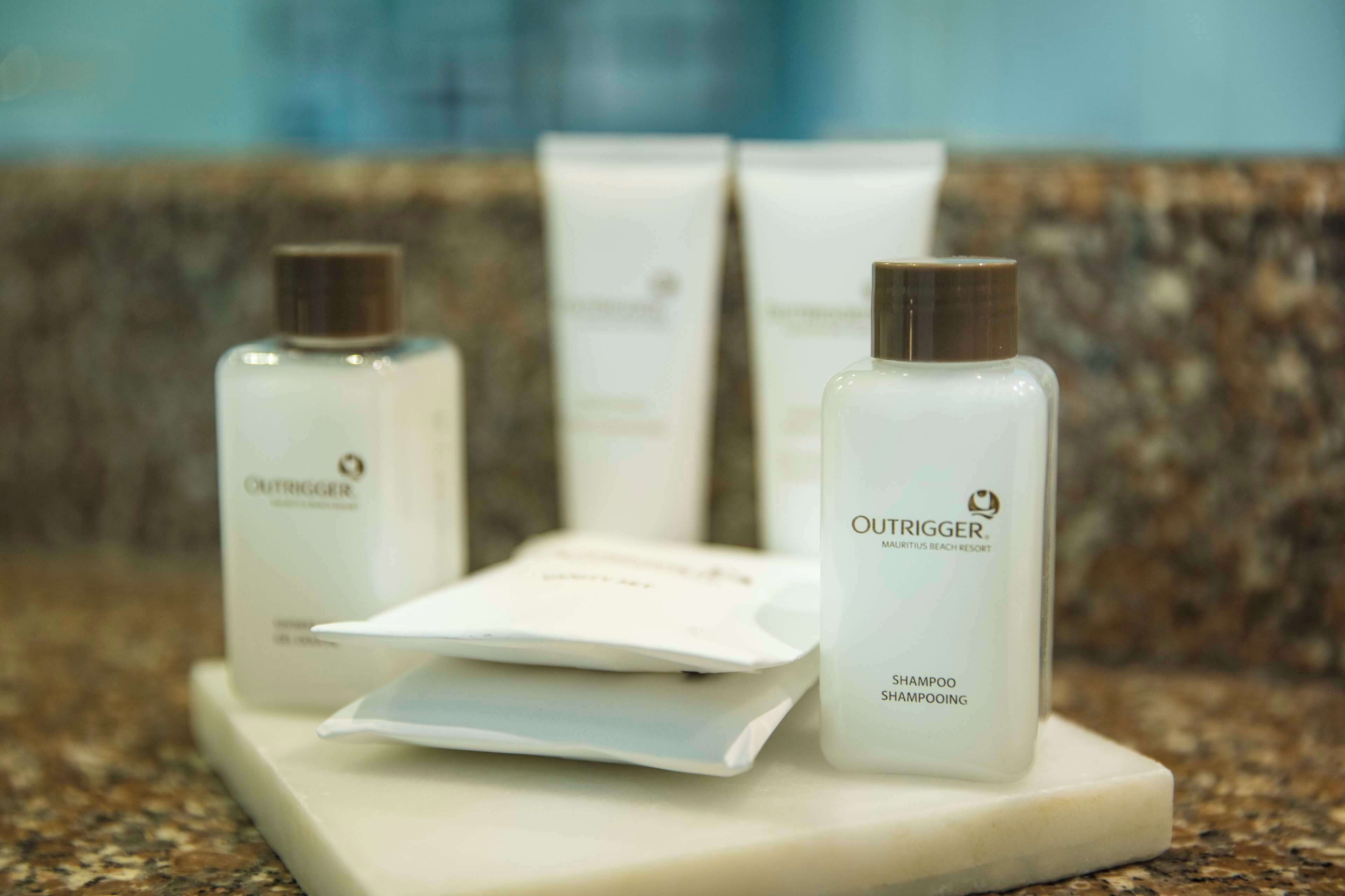 A set of white Outrigger shampoo bottles and packaging on a marble surface.