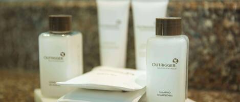 A set of white Outrigger shampoo bottles and packaging on a marble surface.