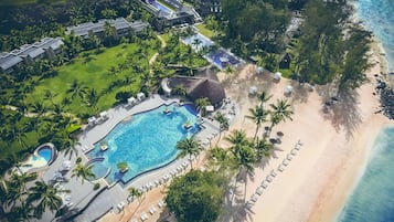 Vista aerea di un resort con piscina, spiaggia e palme.