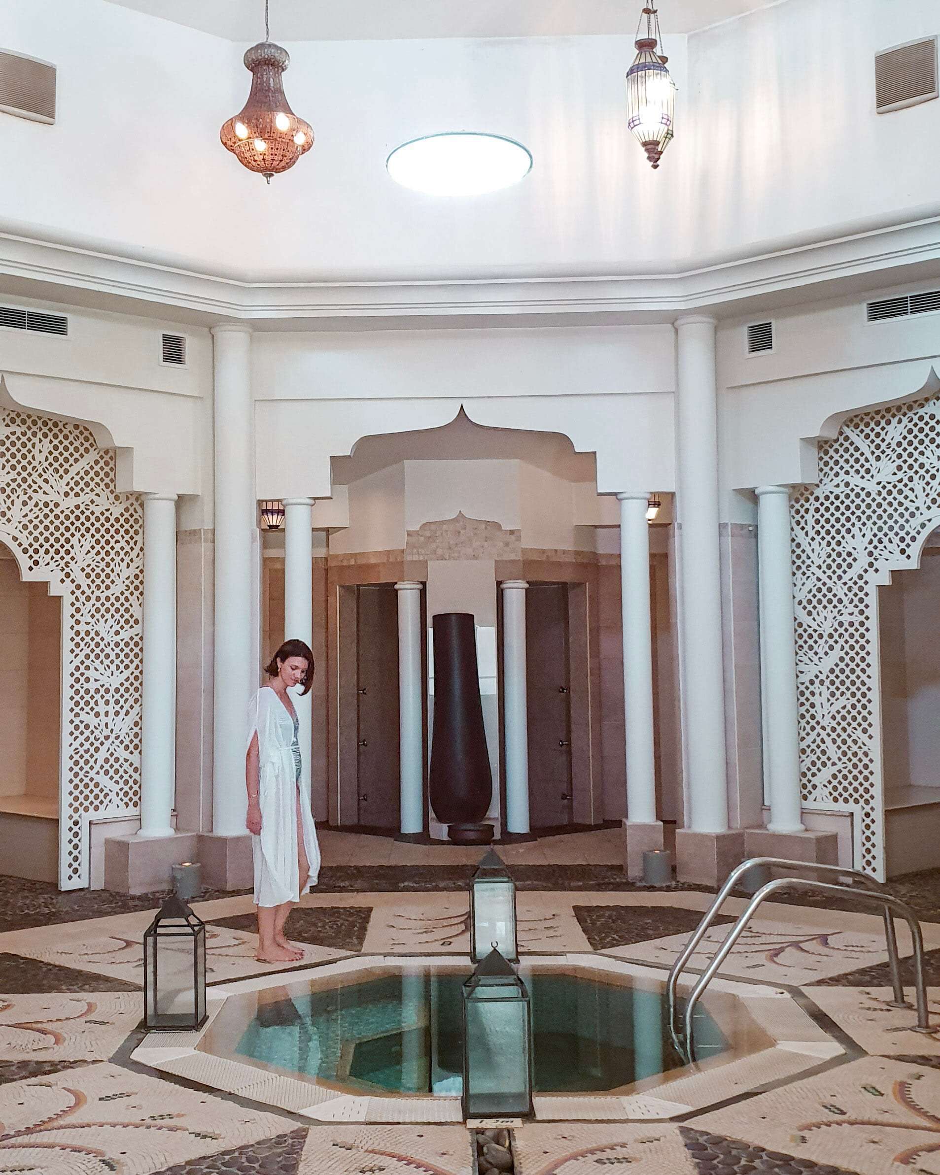 Amplio espacio interior con piscina central, columnas ornamentadas e iluminación decorativa.