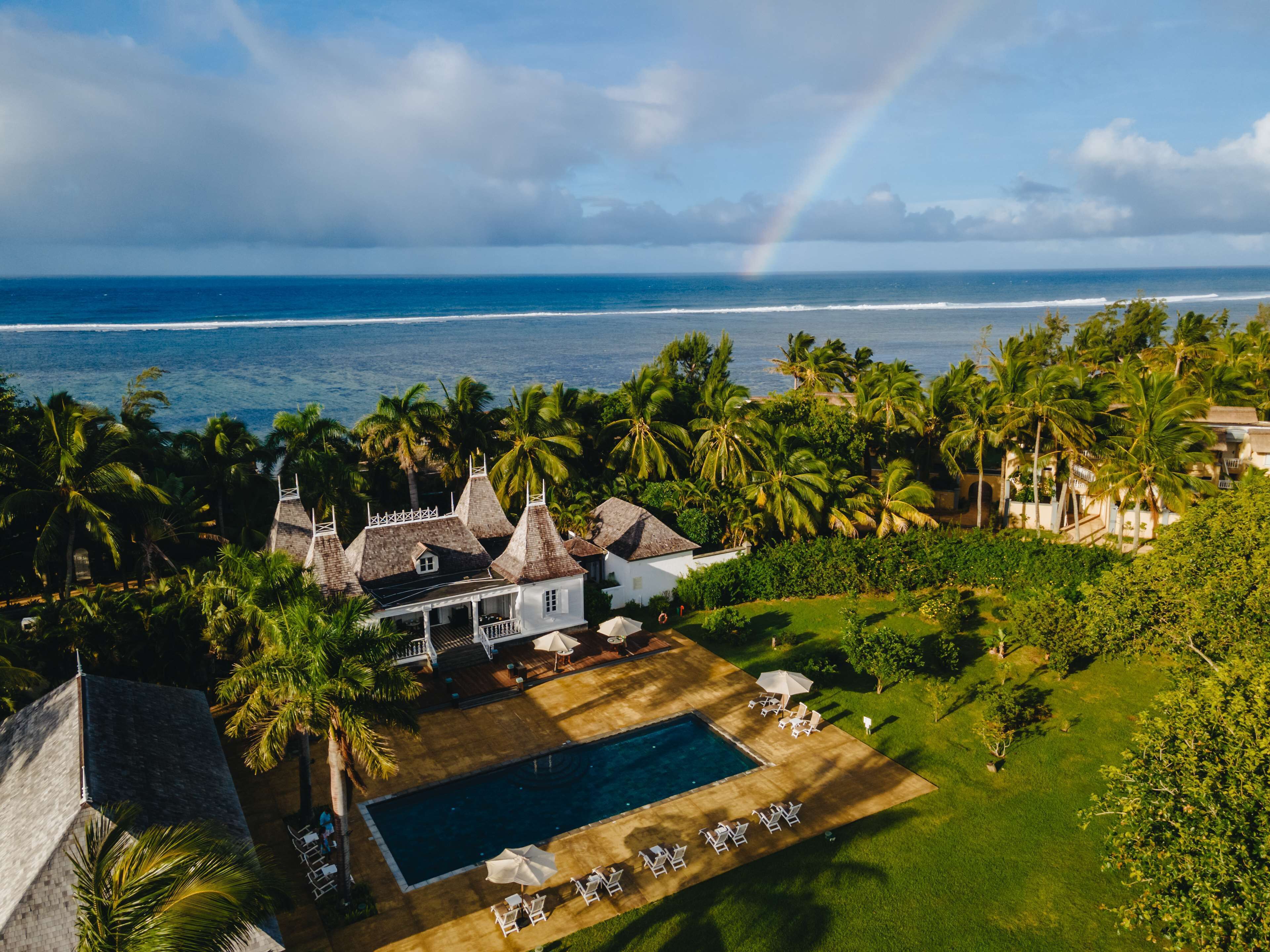 A resort with a swimming pool, palm trees, and ocean views.