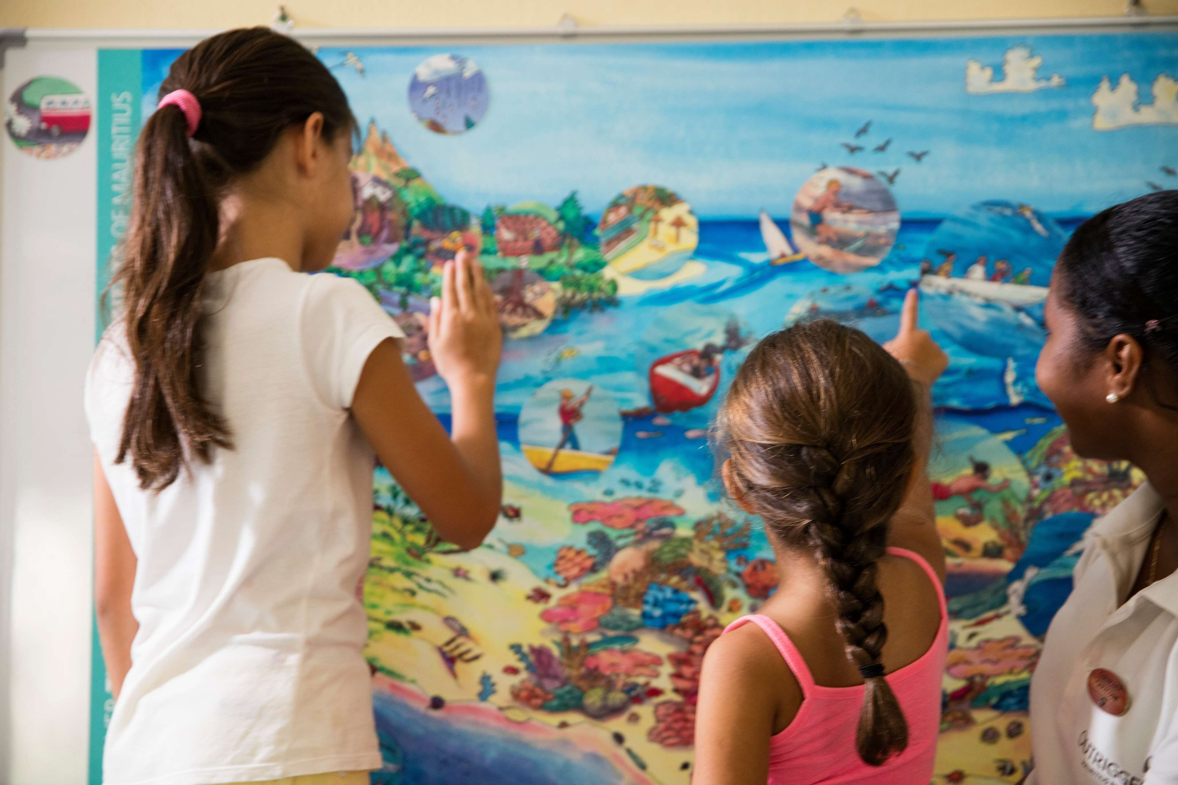 A classroom with a colorful mural on the wall, a whiteboard, and a poster of Mauritius.