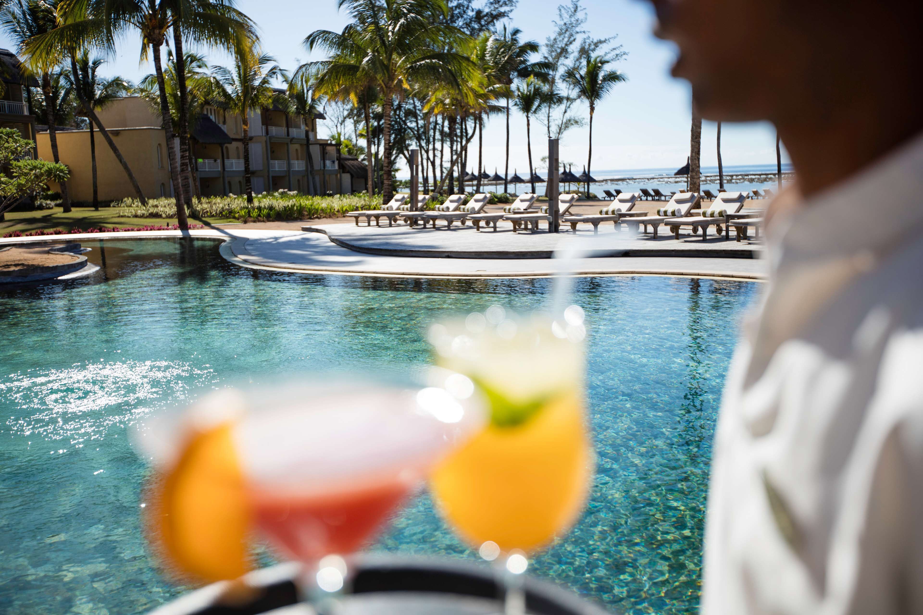 A poolside view with lounge chairs and a clear view of the ocean.