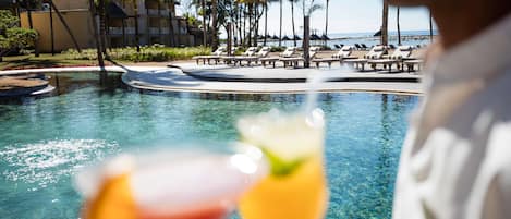 A poolside view with lounge chairs and a clear view of the ocean.