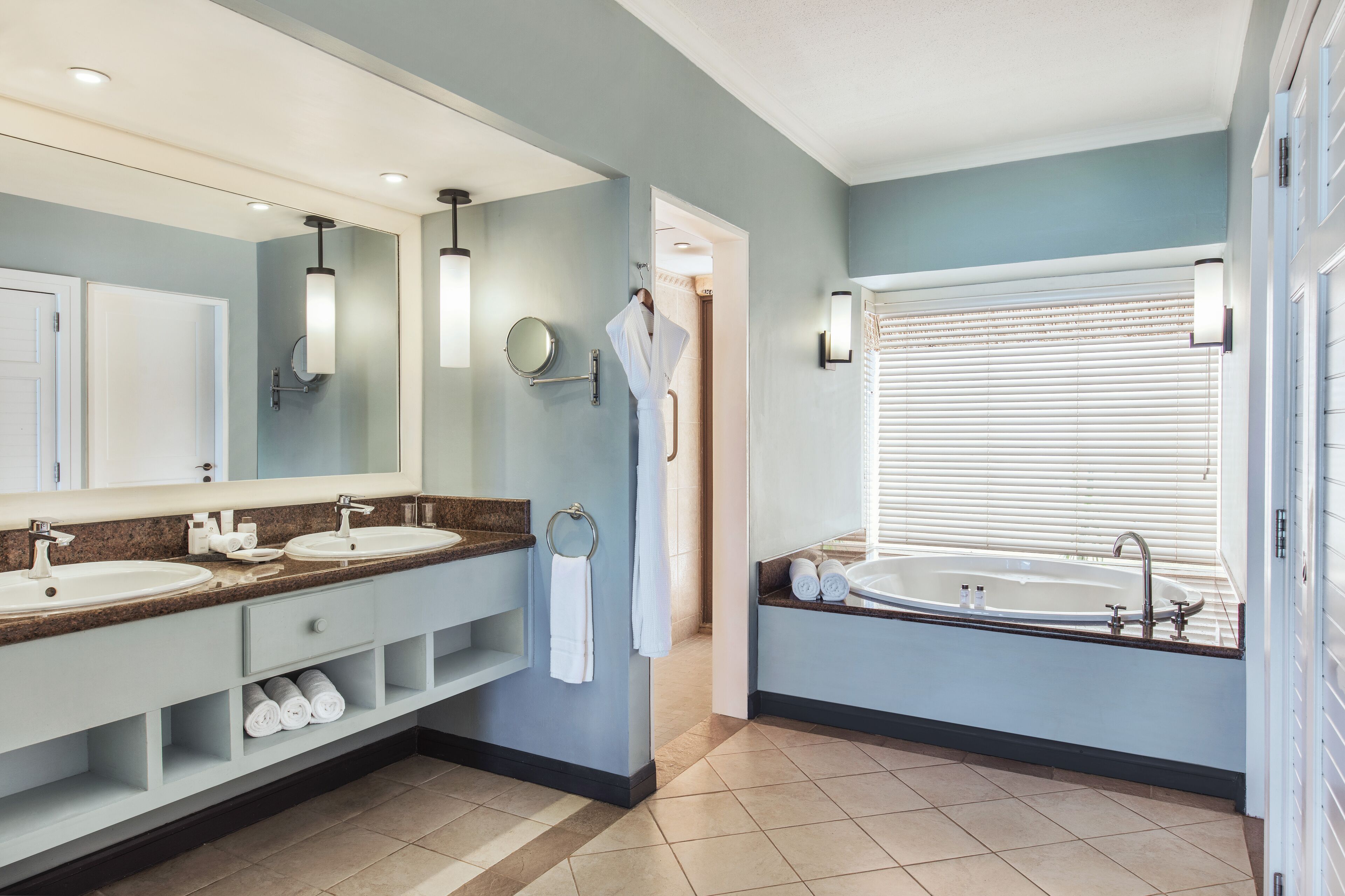 A modern bathroom with two sinks, a large bathtub, and a walk-in shower.