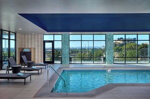 Una piscina interior con sillones de descanso y vistas de la ciudad.