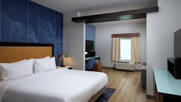 A hotel room with a large bed, a desk, a television, and a window with curtains.