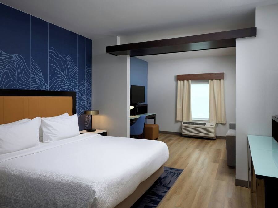 A hotel room with a large bed, a desk, a television, and a window with curtains.