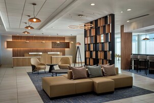 Un moderno vestíbulo de hotel con un sofá modular, una recepción y una estantería.