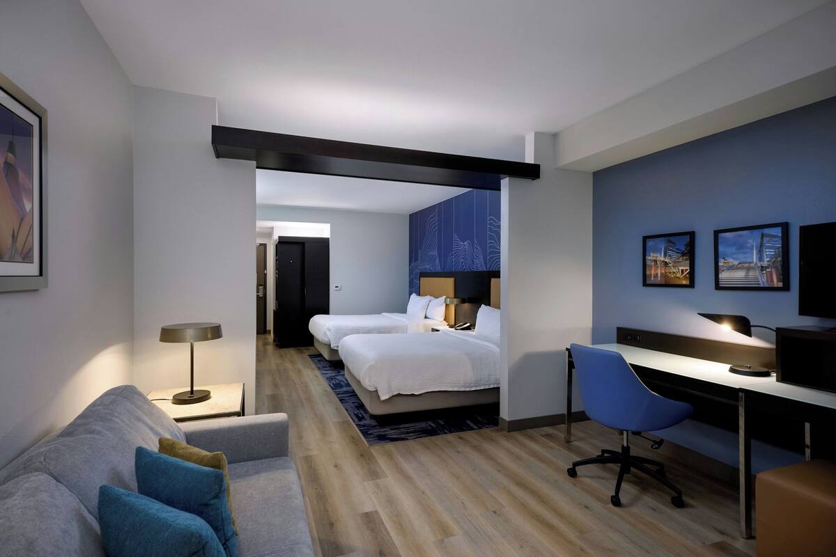 A modern hotel room with a bed, desk, and seating area.