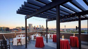 A rooftop dining area with tables set for two, featuring a city skyline view in the background. - Fairfield Inn & Suites by Marriott Denver Downtown (Denver)