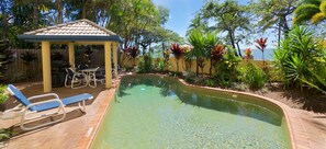 Relax by the pool surrounded by a lush garden and a shaded gazebo.