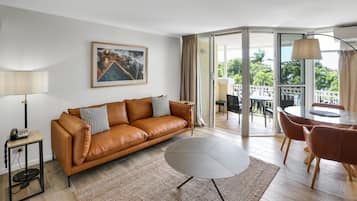 Una sala de estar moderna con un sofá de cuero marrón, una mesa de centro redonda y un comedor con mesa y sillas.