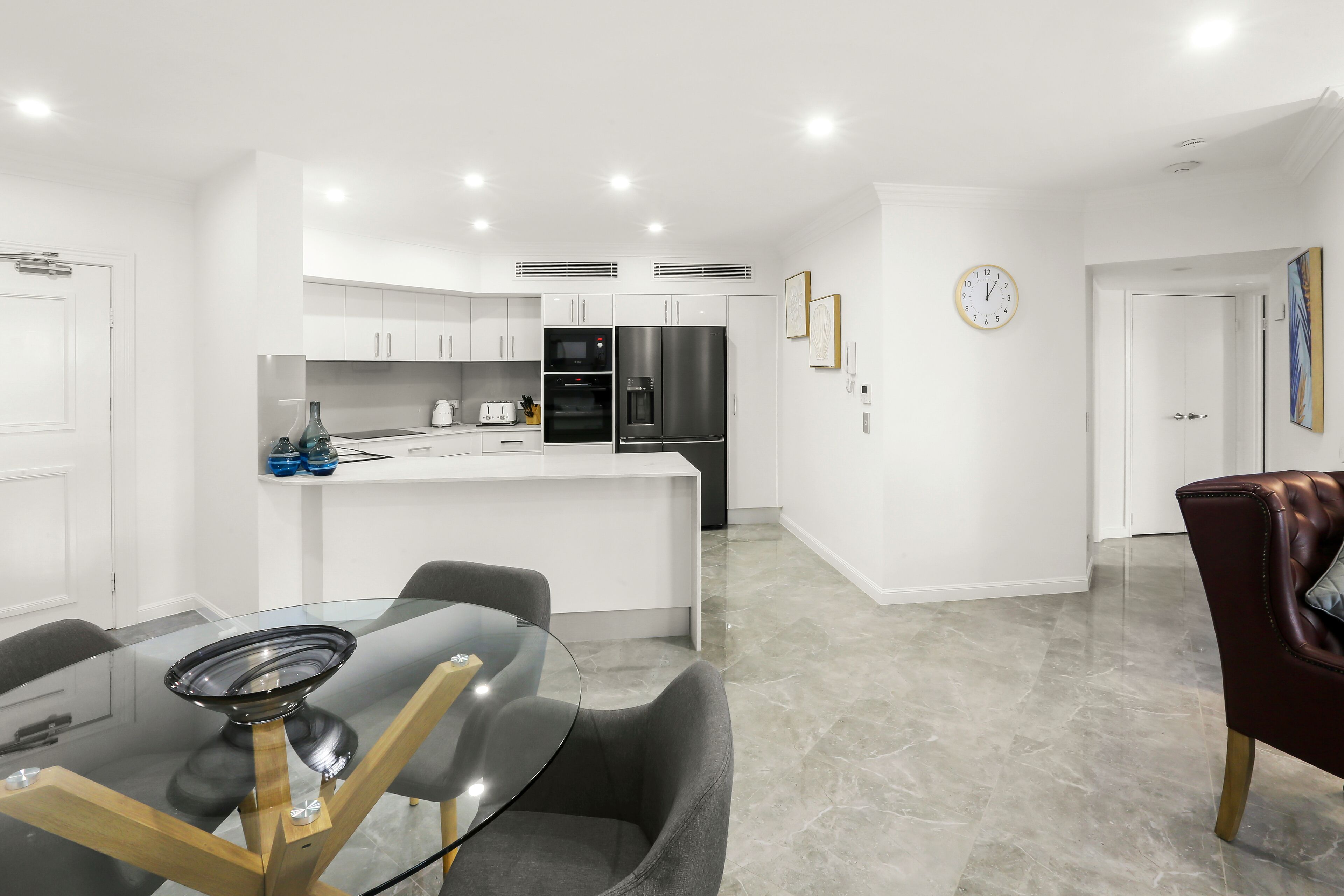 A modern kitchen with white cabinetry, a central island, and stainless steel appliances.