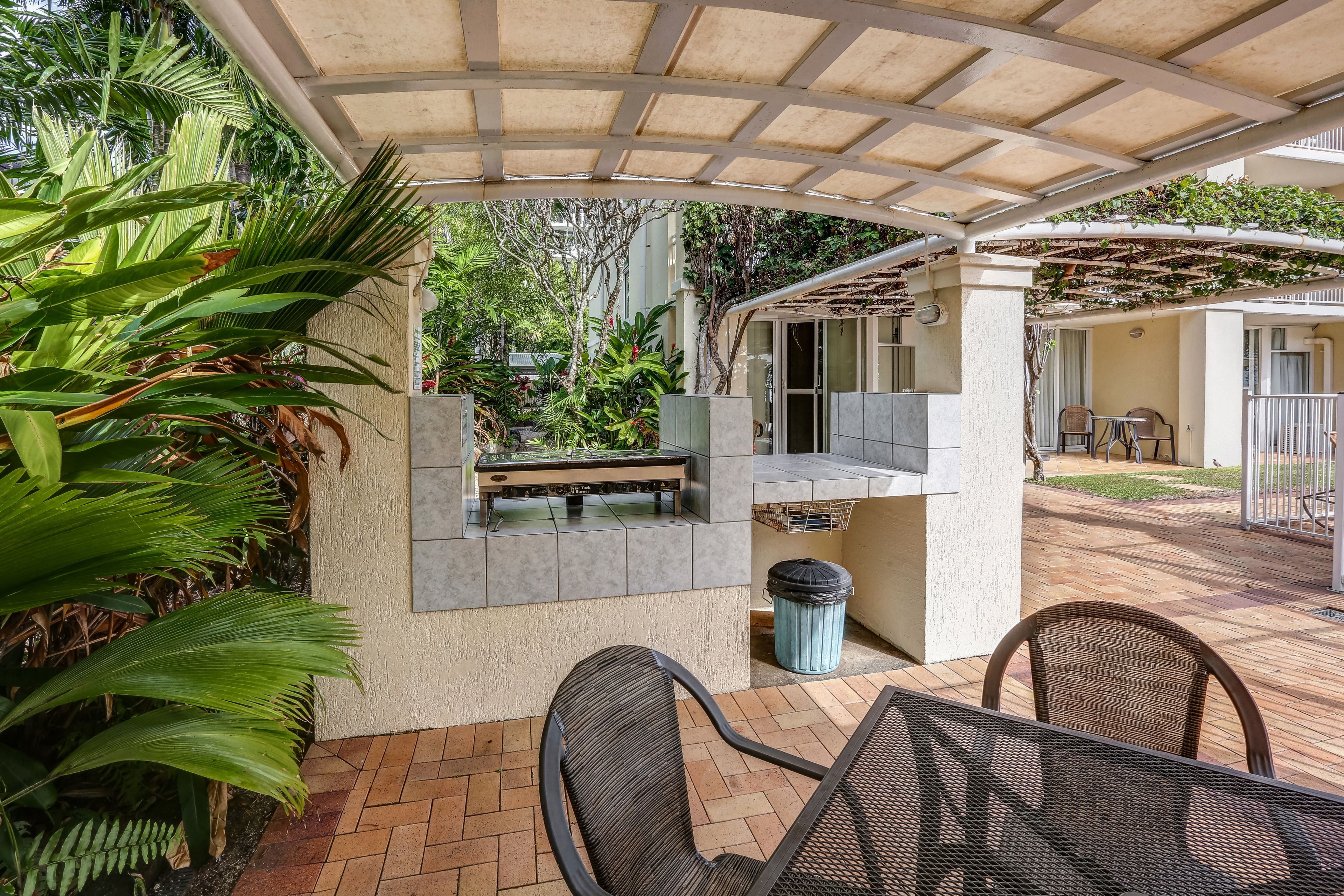 A covered patio area with a seating arrangement, a small water feature, and surrounding greenery.