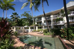 Relax by the pool surrounded by lush tropical vegetation and palm trees.