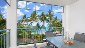A balcony with a glass table, two chairs, and a white lantern. - On the Beach Holiday Apartments (Trinity Beach)