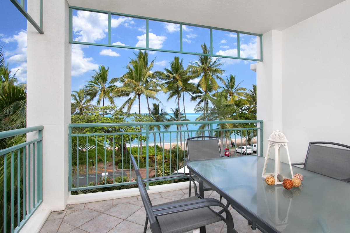 A balcony with a glass table, chairs, and a white lantern.