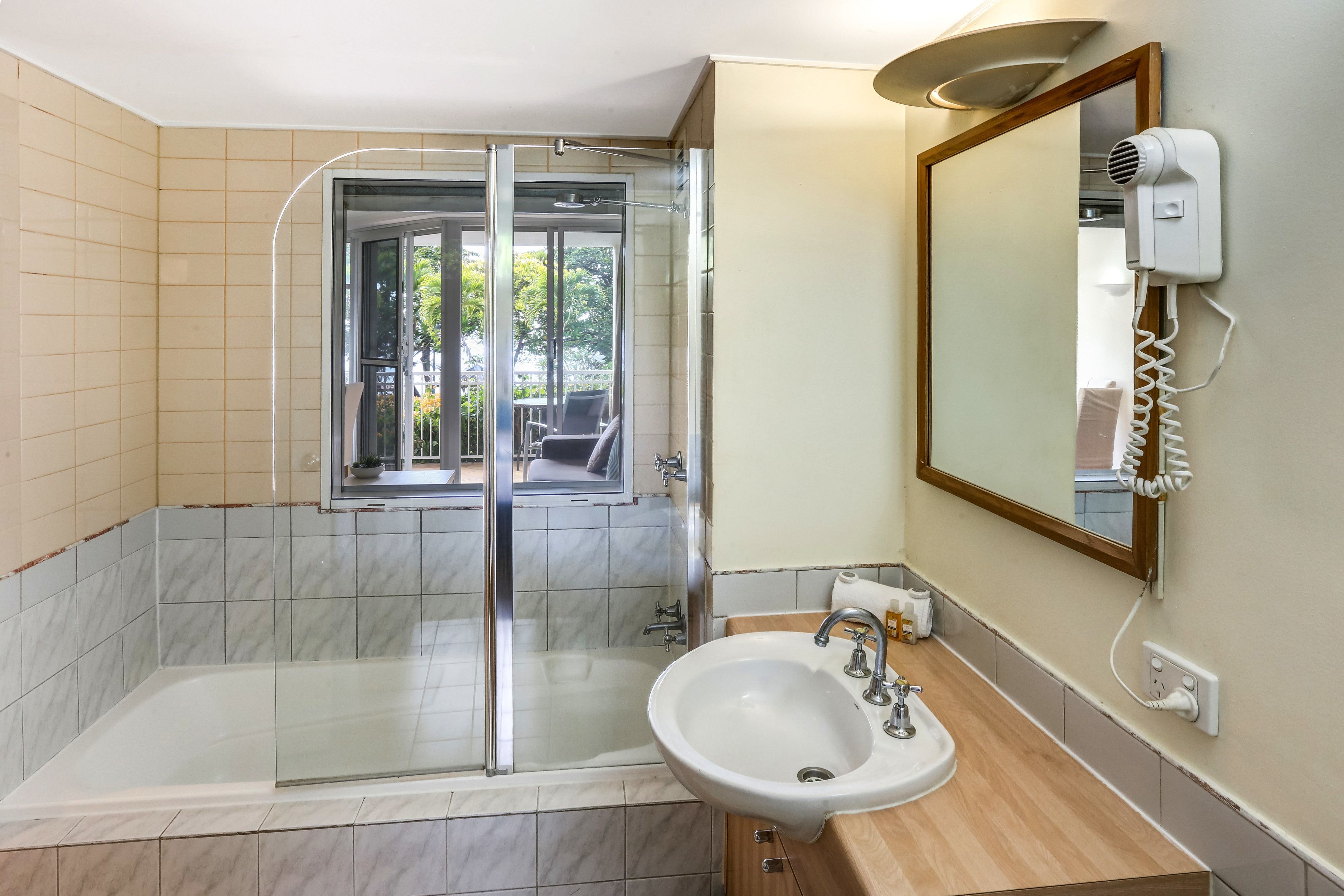 Une salle de bain moderne dotée d’une douche à parois de verre, d’un lavabo et d’un sèche-cheveux fixé au mur.