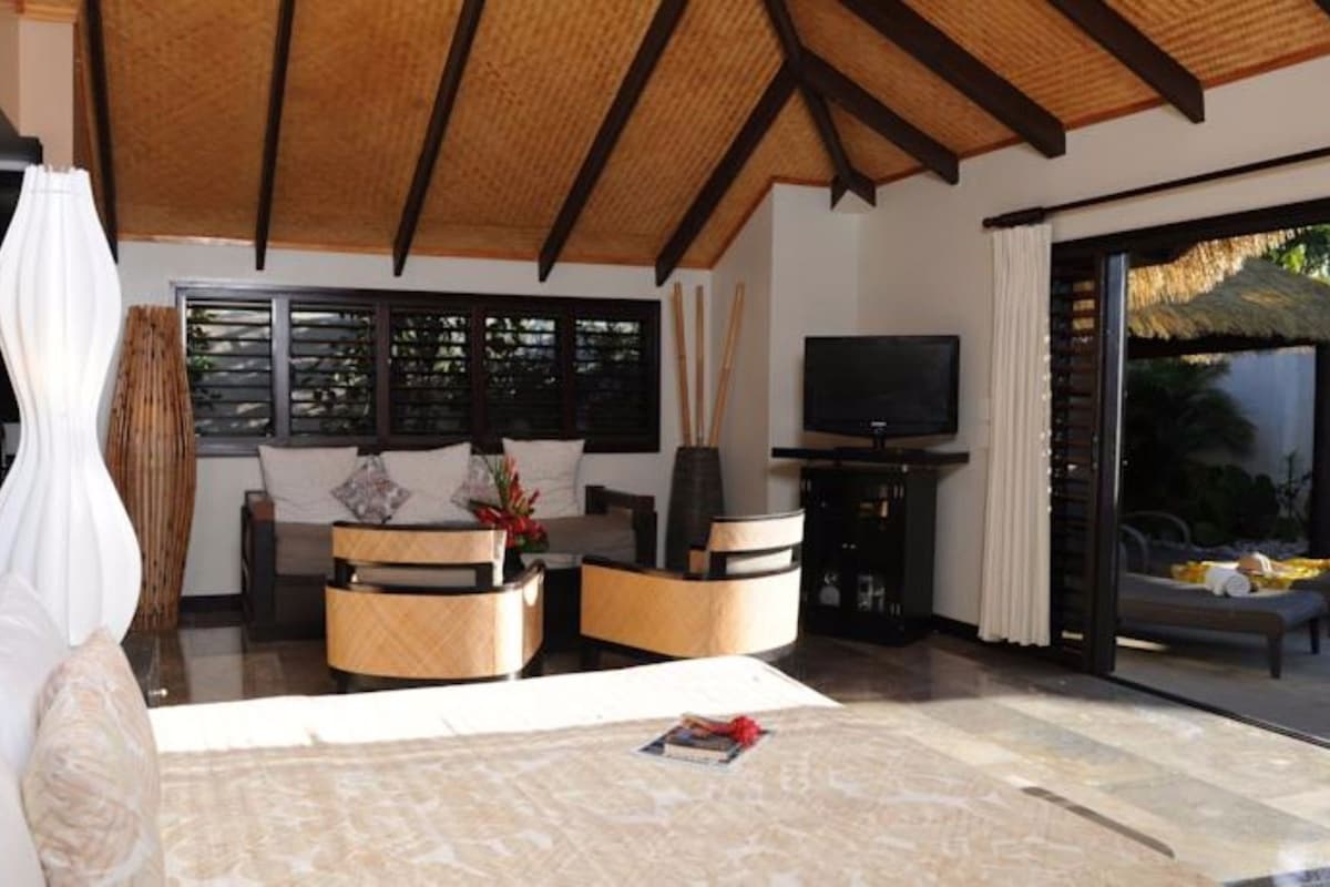 A modern living room with a sofa, a coffee table, a TV, and a large window with blinds.