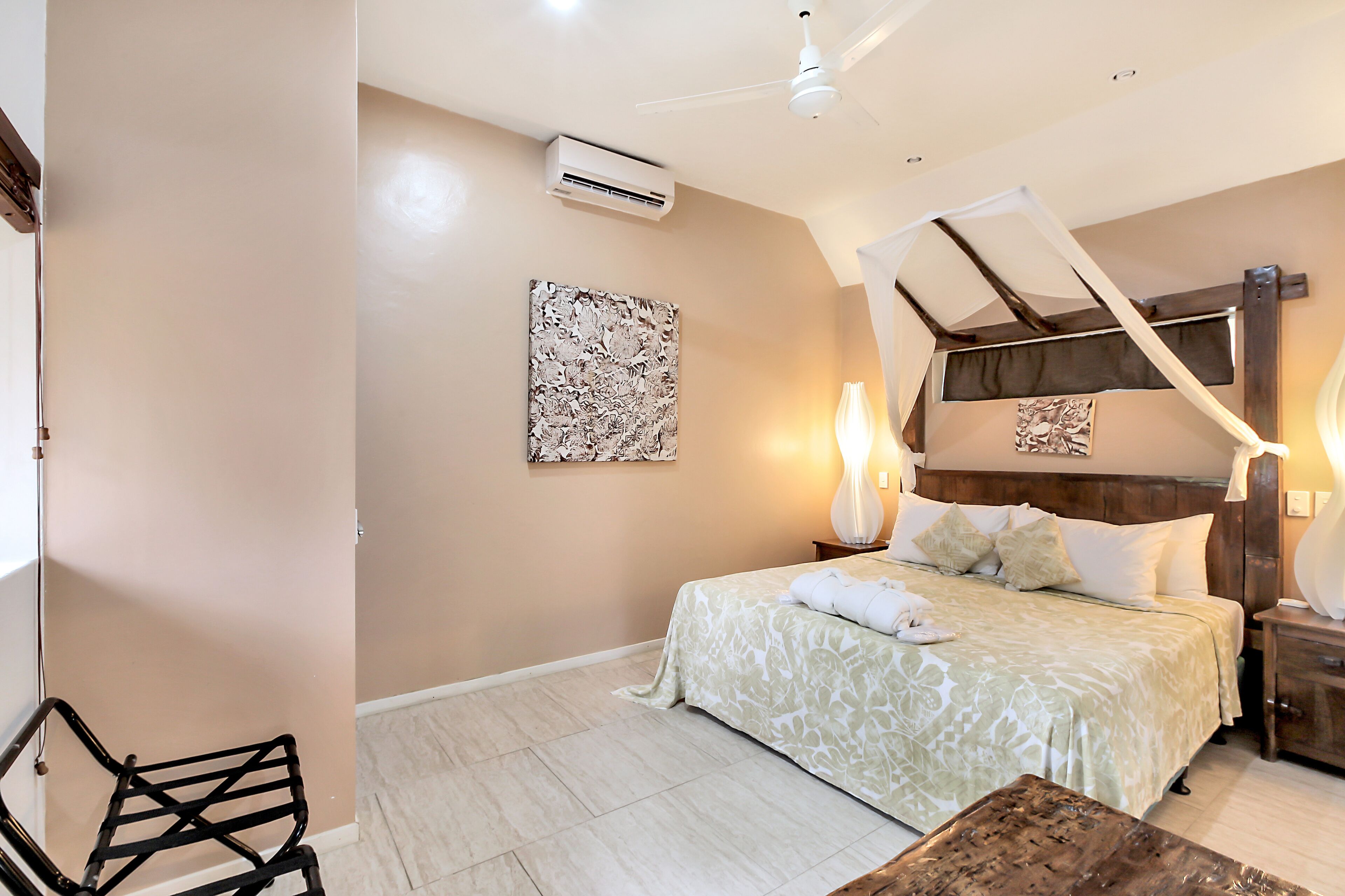 A bedroom with a bed, bedside tables, a chair, and an air conditioning unit.
