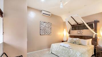 A bedroom with a bed, bedside tables, a chair, and an air conditioning unit.