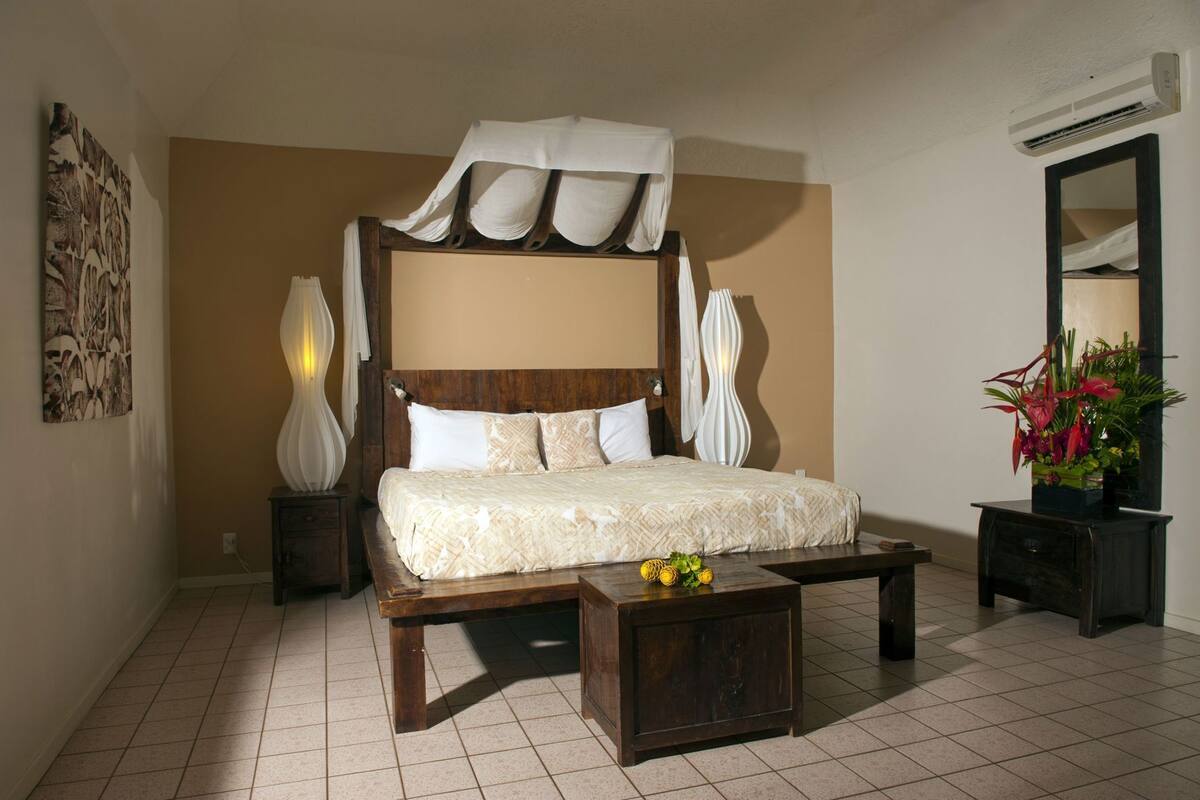 Un dormitorio con una cama grande, una mesita de noche, un espejo y aire acondicionado instalado en la pared.
