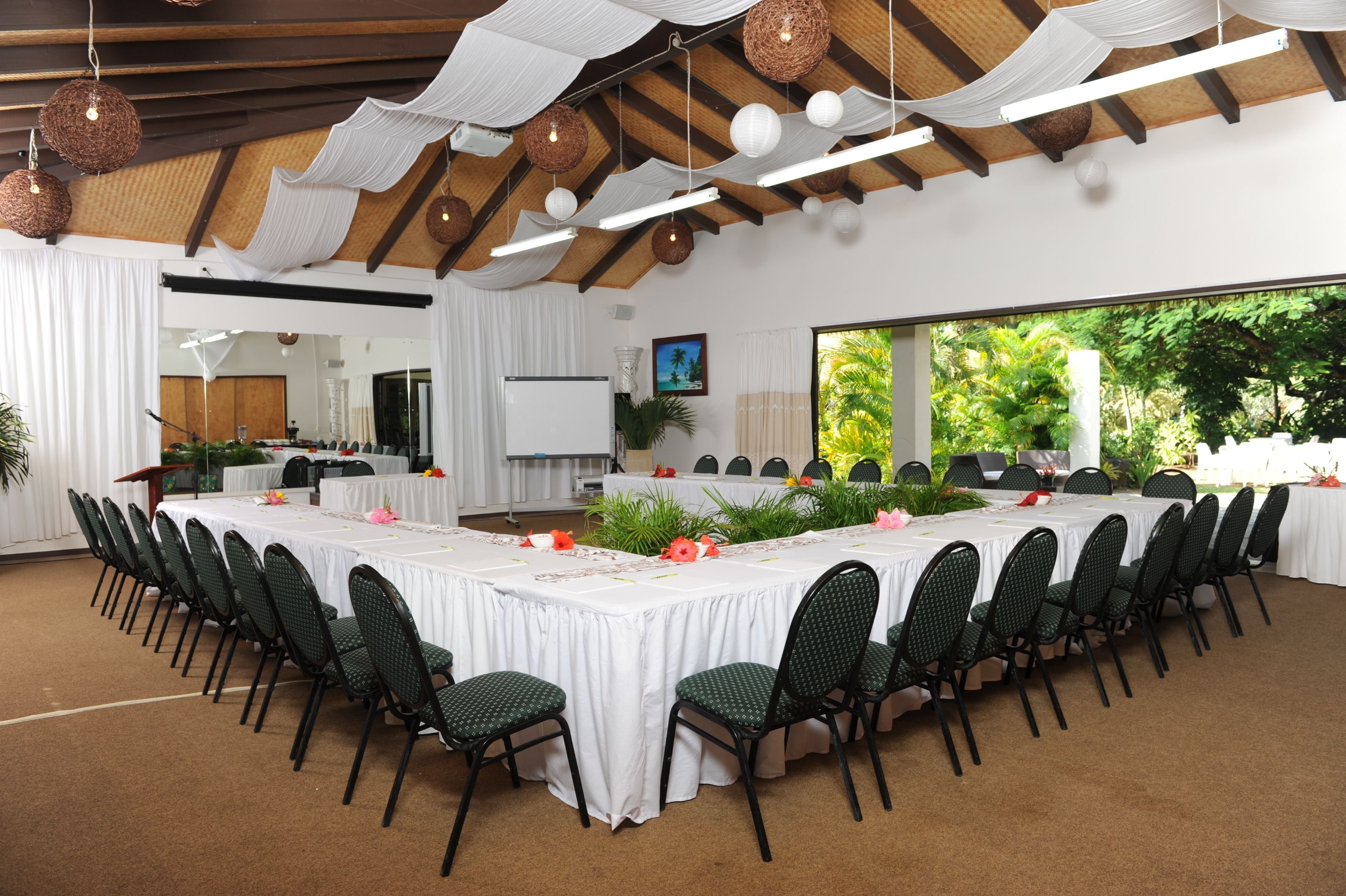 A conference room with a long table, chairs, and a white backdrop.