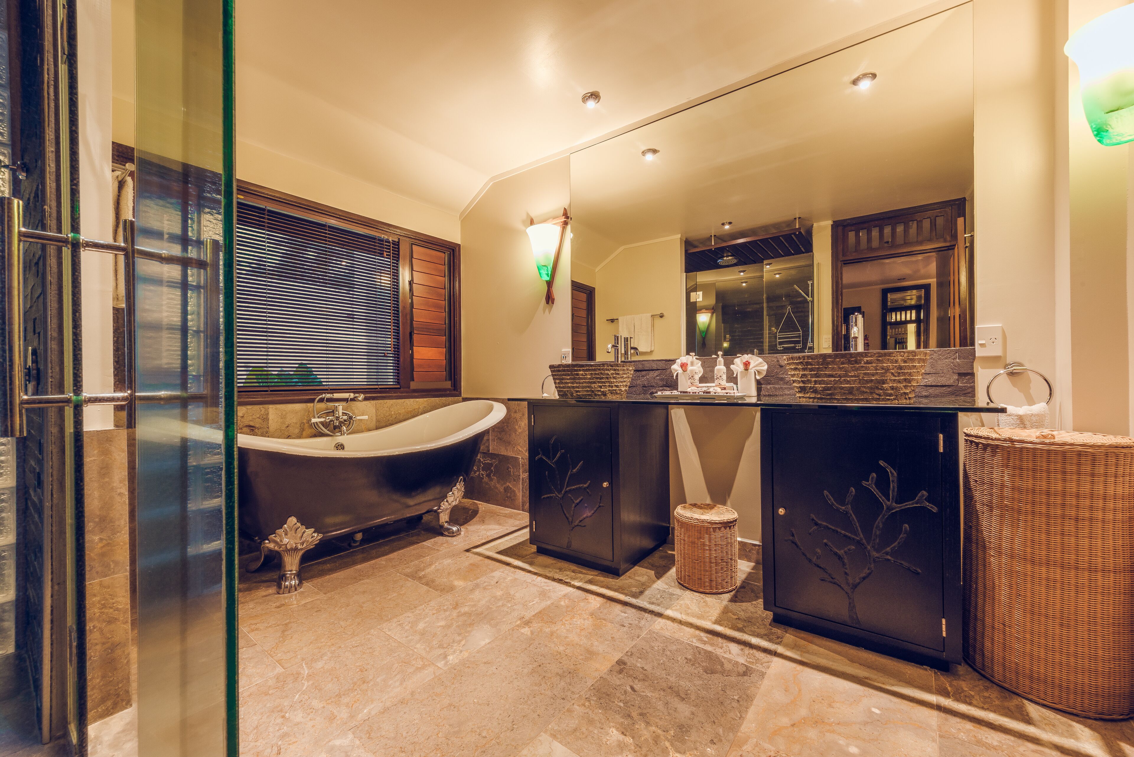 A modern bathroom with a freestanding bathtub, a large mirror, and a vanity with a marble countertop.