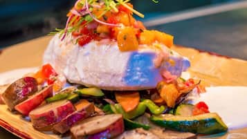 A plate with a fish fillet, roasted vegetables, and a salsa topping.