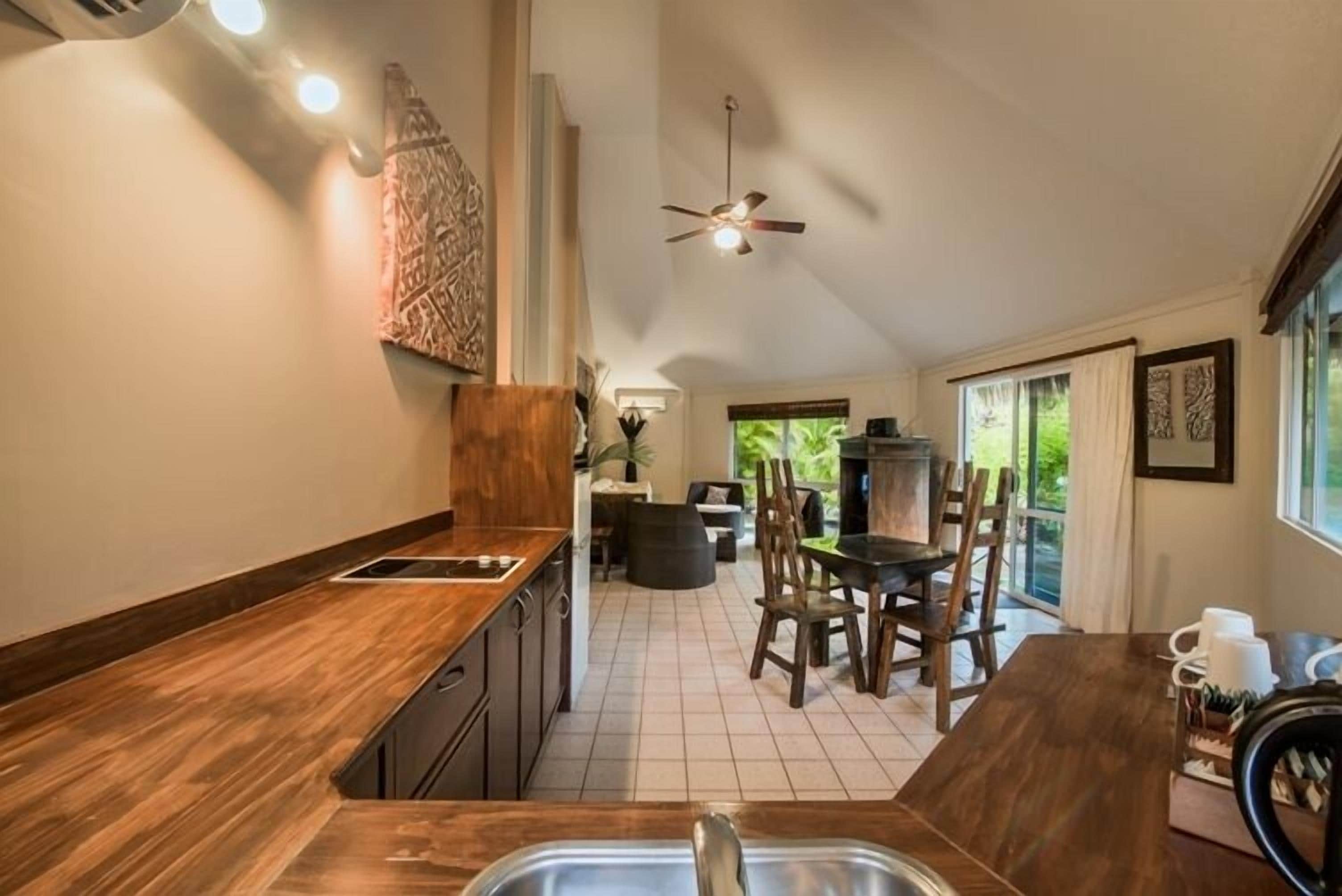 A kitchen with a wooden countertop, a sink, and a dining area with chairs and a table.