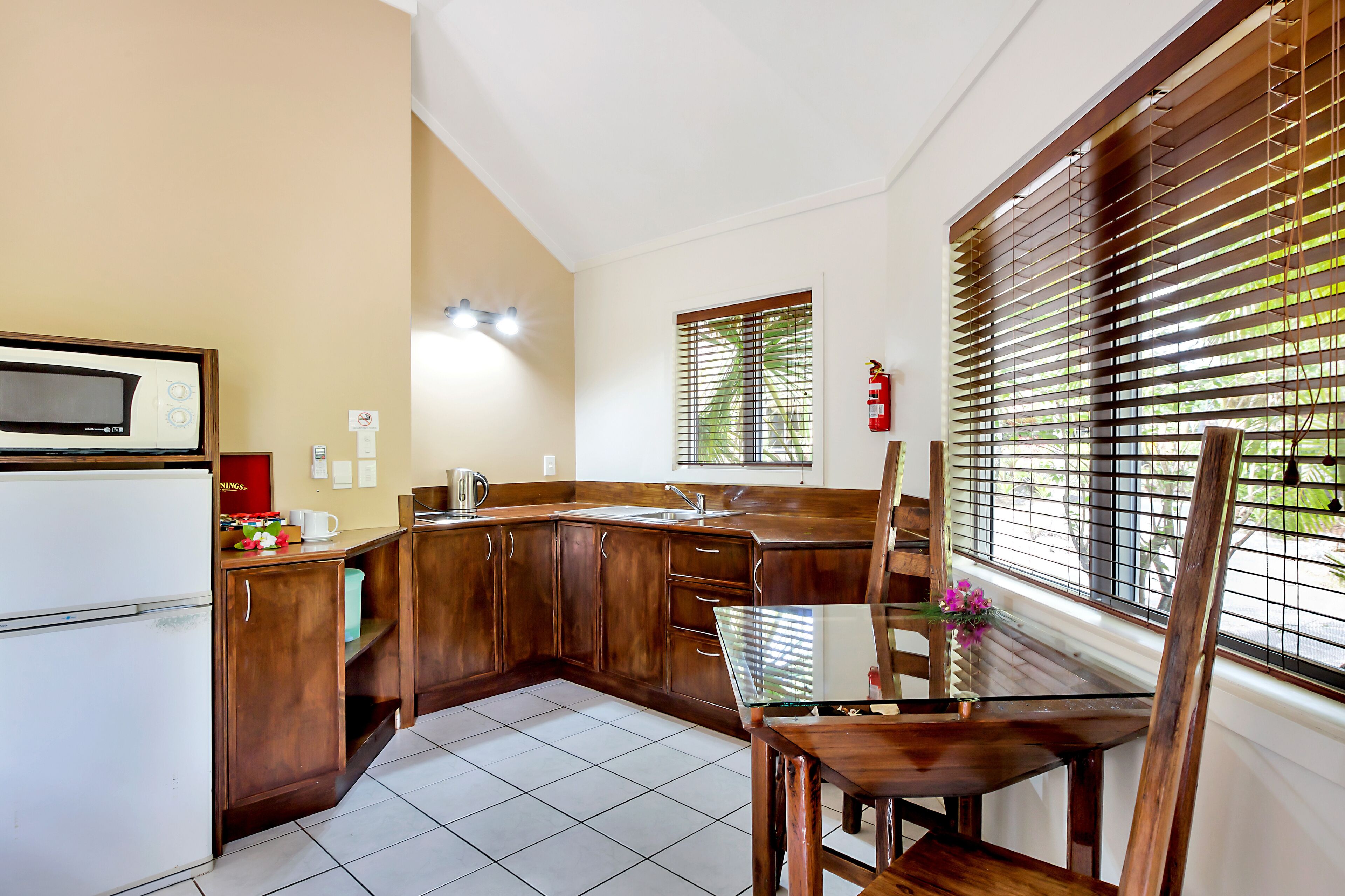 A kitchen with wooden cabinets, a microwave, a sink, and a dining table with chairs.