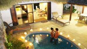 A pool area with a couple standing in the water, surrounded by lounge chairs and a thatched-roof structure. - Crown Beach Resort & Spa (Rarotonga)