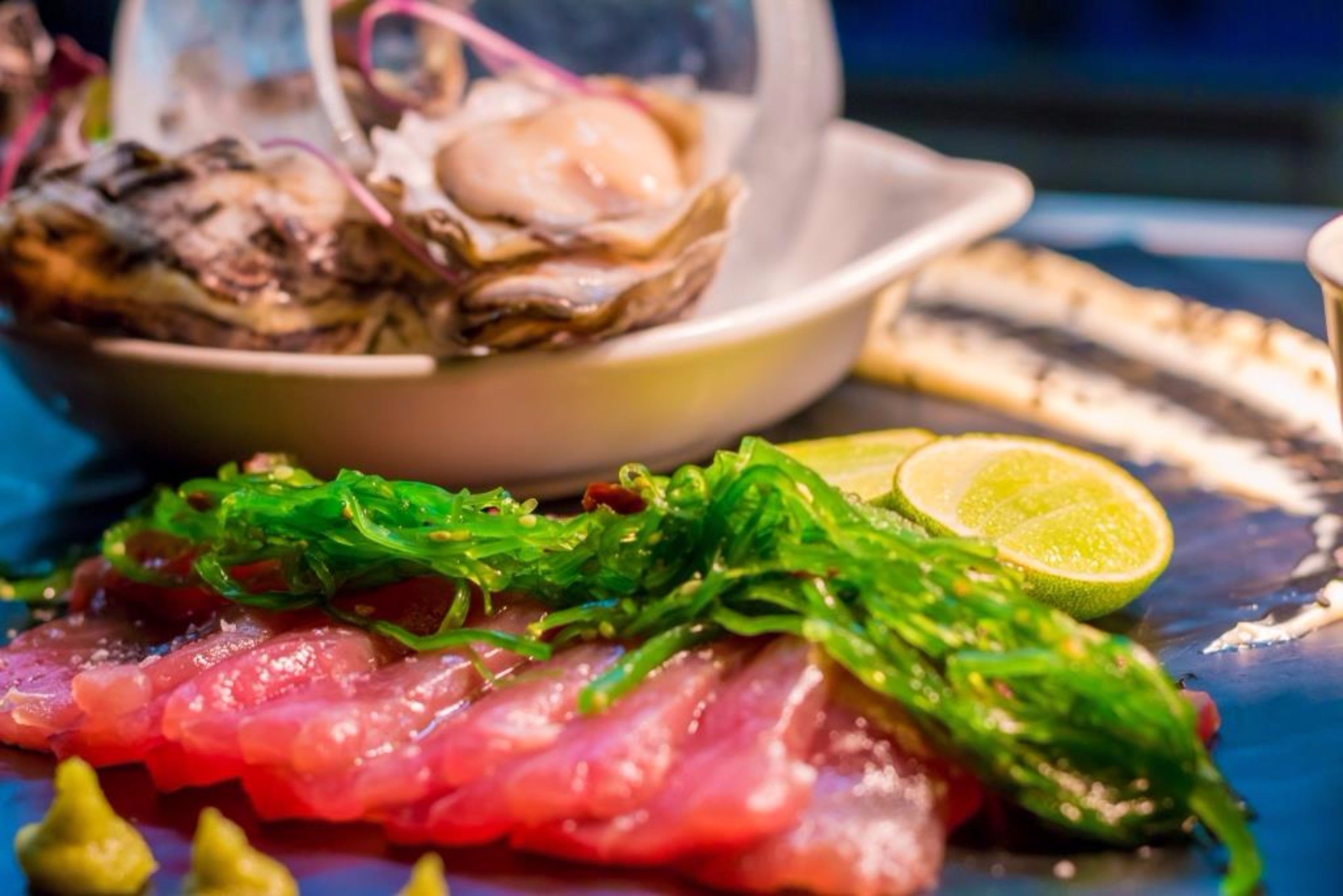 A plate with raw fish, seaweed, and a lime wedge.