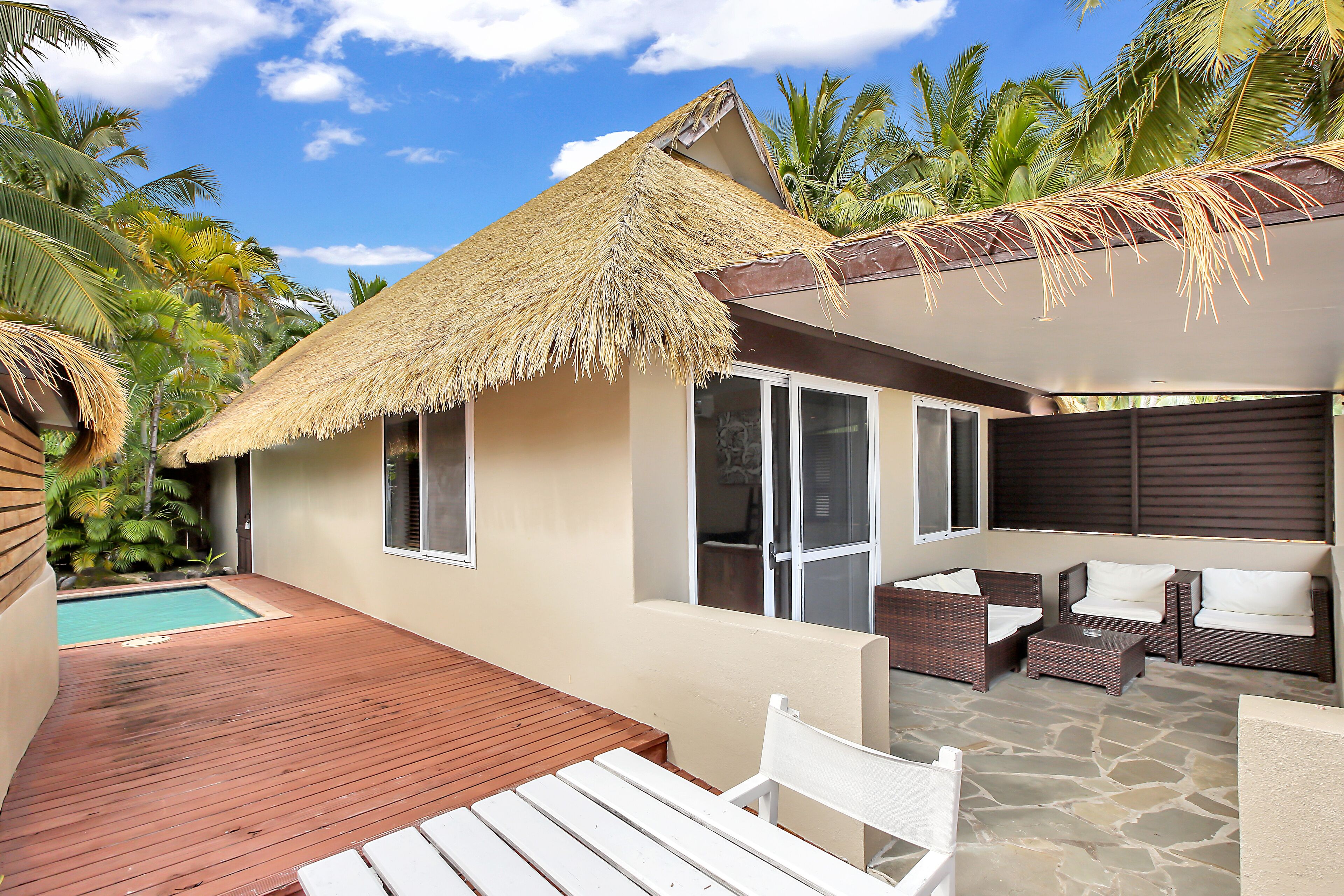 A resort with a pool, thatched-roof structures, and outdoor seating.
