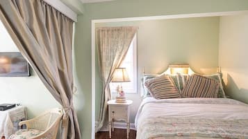 A bedroom with a bed, bedside table, lamp, and curtains.