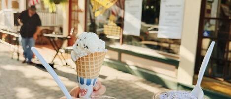 A person holding two ice cream cones and a cup of ice cream.